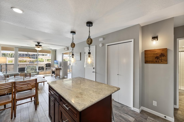 kitchen with ceiling fan, hanging light fixtures, dark brown cabinetry, and a textured ceiling