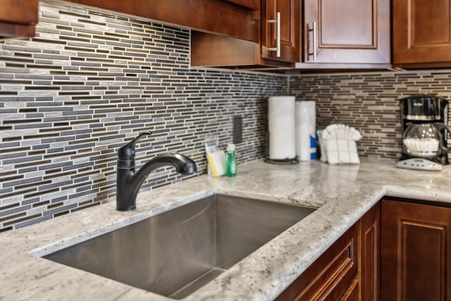 kitchen featuring decorative backsplash, sink, and light stone countertops