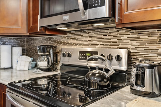 room details featuring tasteful backsplash, light stone countertops, and appliances with stainless steel finishes