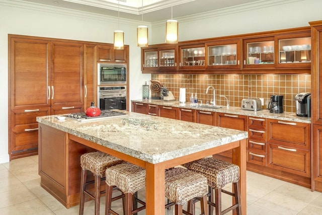 kitchen with a kitchen island, pendant lighting, sink, backsplash, and stainless steel appliances