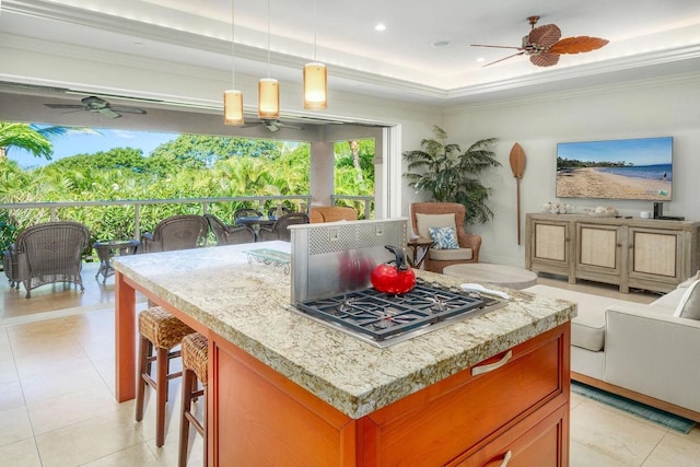 kitchen featuring ceiling fan, stainless steel gas stovetop, a tray ceiling, and hanging light fixtures