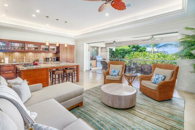 living room with a raised ceiling, ornamental molding, and ceiling fan