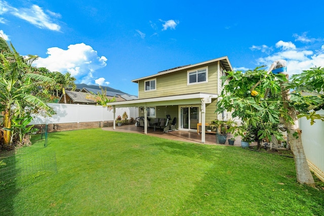 rear view of property featuring a yard, a fenced backyard, and a patio