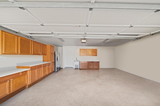 garage with stainless steel fridge with ice dispenser, a garage door opener, and a sink