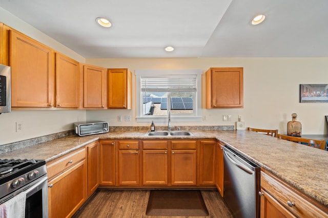 kitchen featuring light countertops, recessed lighting, appliances with stainless steel finishes, wood finished floors, and a sink