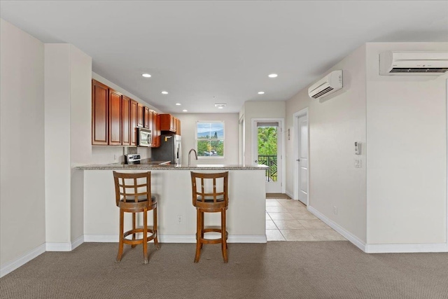 kitchen with light carpet, a breakfast bar area, a wall unit AC, and stainless steel appliances