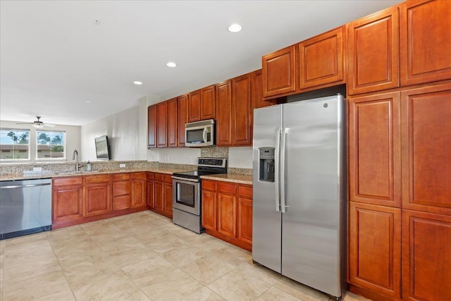 kitchen featuring light stone countertops, stainless steel appliances, sink, backsplash, and ceiling fan