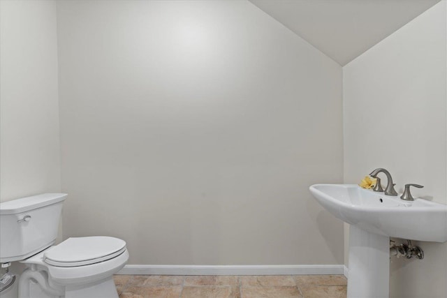 bathroom with sink, toilet, and vaulted ceiling