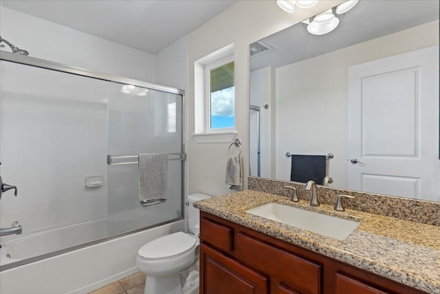 full bathroom with combined bath / shower with glass door, toilet, tile patterned floors, and vanity