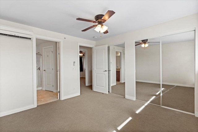 unfurnished bedroom featuring light carpet, a wall mounted air conditioner, ensuite bath, and ceiling fan