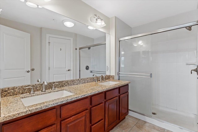 bathroom with a shower with door, vanity, and tile patterned flooring