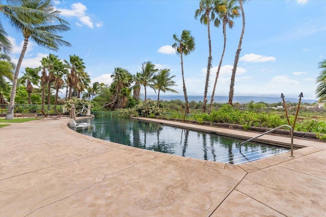 view of pool with a water view and a patio area