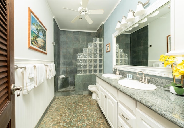 bathroom with ceiling fan, toilet, tiled shower, vanity, and crown molding