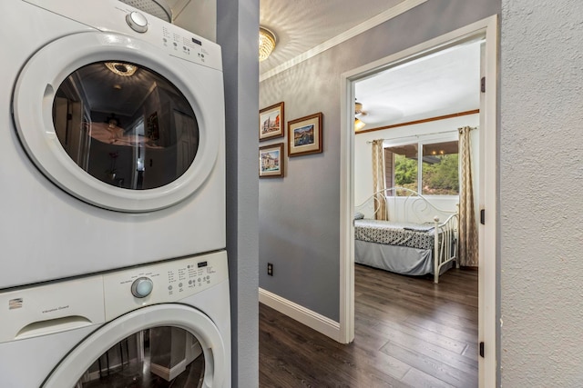 laundry room with crown molding, stacked washing maching and dryer, and dark hardwood / wood-style floors