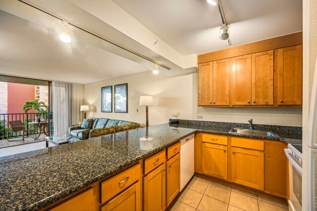 kitchen featuring white appliances, track lighting, dark stone counters, and sink