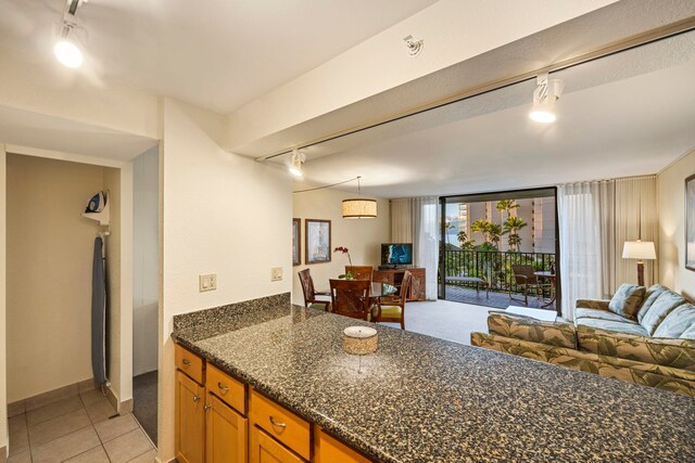 kitchen with decorative light fixtures, light tile patterned flooring, dark stone counters, and track lighting