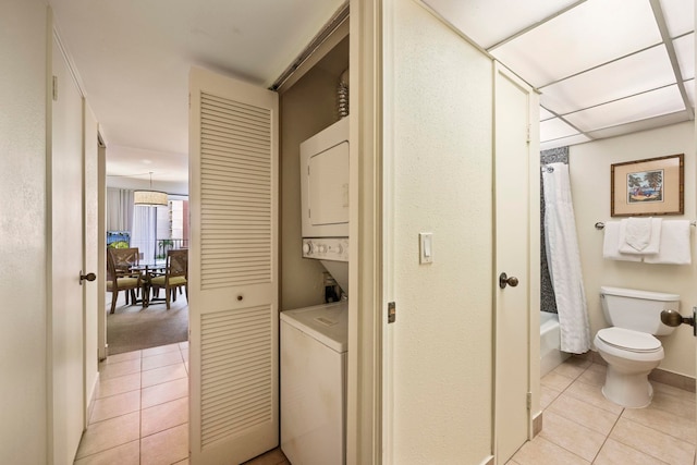 washroom with stacked washing maching and dryer and light tile patterned floors