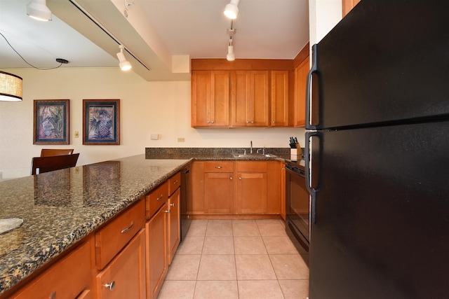 kitchen featuring sink, rail lighting, dark stone countertops, light tile patterned floors, and black appliances