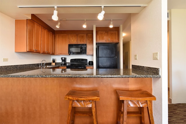 kitchen with black appliances, kitchen peninsula, sink, and rail lighting