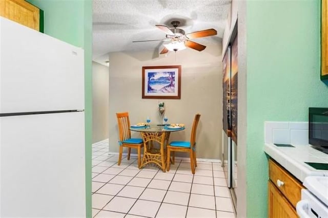 tiled dining room with ceiling fan and a textured ceiling