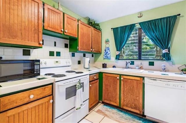 kitchen with light tile patterned floors, white appliances, sink, and backsplash