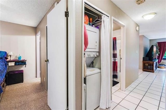 corridor featuring light colored carpet, a textured ceiling, and stacked washer and clothes dryer