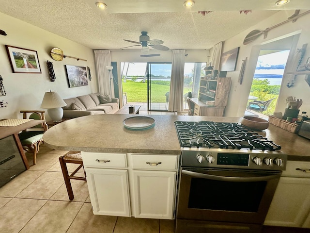 kitchen with white cabinetry, light tile patterned flooring, stainless steel gas range, and a textured ceiling