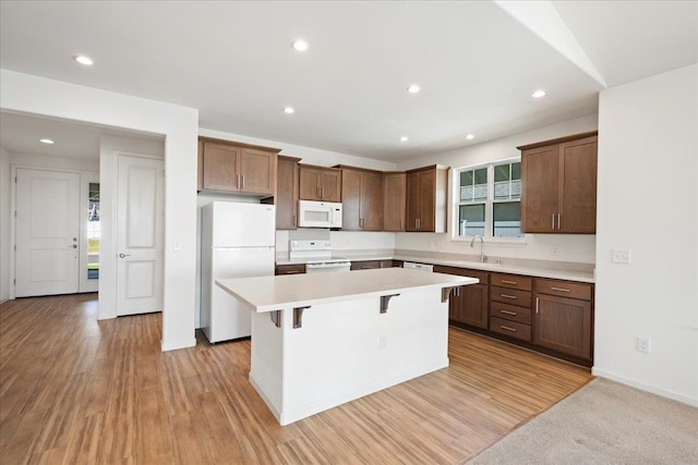 kitchen with a sink, white appliances, a kitchen island, and plenty of natural light