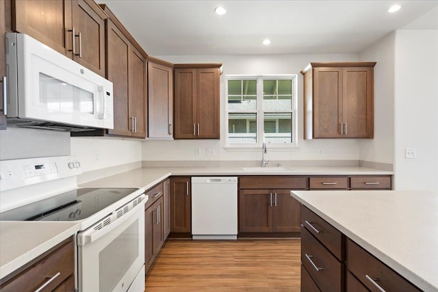 kitchen featuring light wood-style flooring, a sink, white appliances, light countertops, and recessed lighting