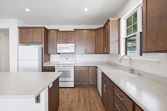 kitchen featuring light countertops, dark wood finished floors, a sink, and white appliances