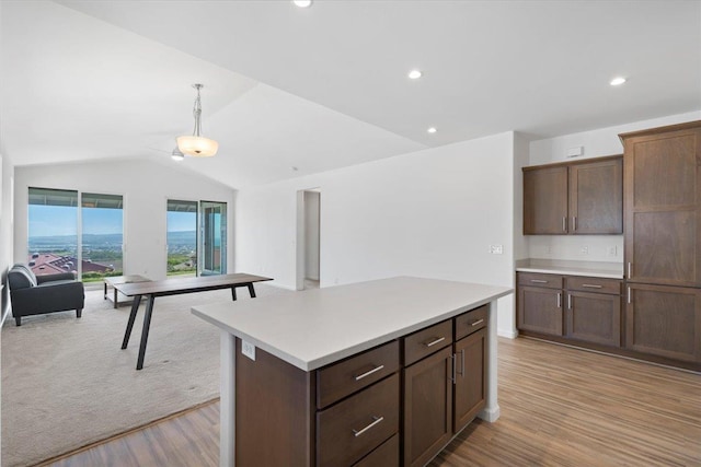 kitchen featuring light wood-style flooring, a center island, open floor plan, vaulted ceiling, and light countertops