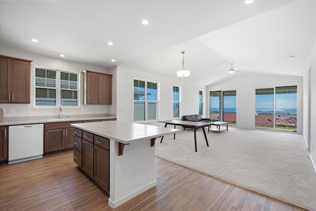 kitchen with light countertops, wood finished floors, a sink, a healthy amount of sunlight, and dishwasher