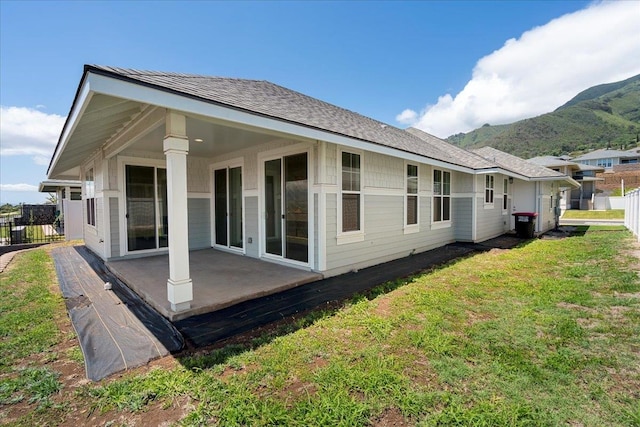 rear view of house featuring a mountain view, a patio area, fence, and a lawn