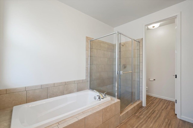 full bath with toilet, wood finished floors, a stall shower, baseboards, and a bath