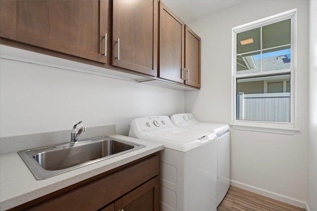 laundry room with wood finished floors, a sink, cabinet space, washer and clothes dryer, and baseboards