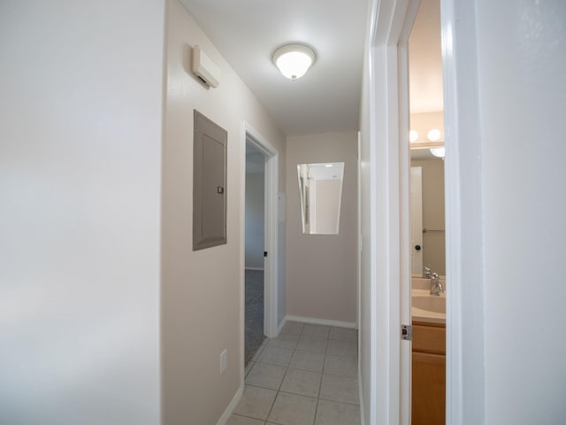 hall with sink, light tile patterned flooring, and electric panel