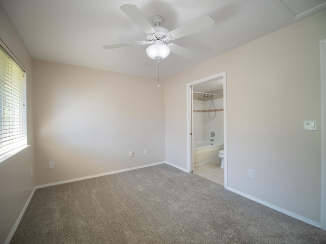 unfurnished bedroom with a walk in closet, ceiling fan, ensuite bathroom, and light carpet