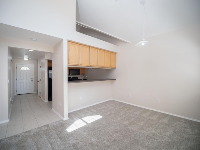 kitchen featuring kitchen peninsula, light brown cabinets, light carpet, and hanging light fixtures