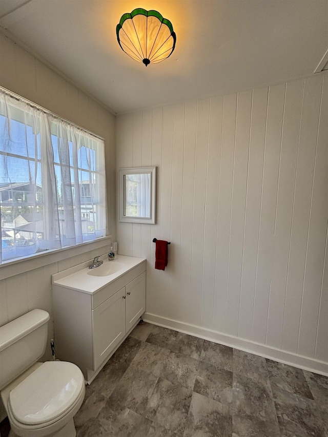 bathroom with toilet, vanity, and baseboards