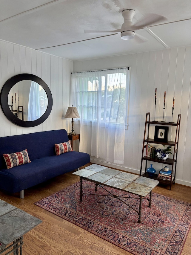 living room featuring baseboards, a ceiling fan, and wood finished floors