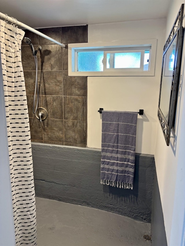 full bathroom featuring a tile shower, a healthy amount of sunlight, and concrete floors