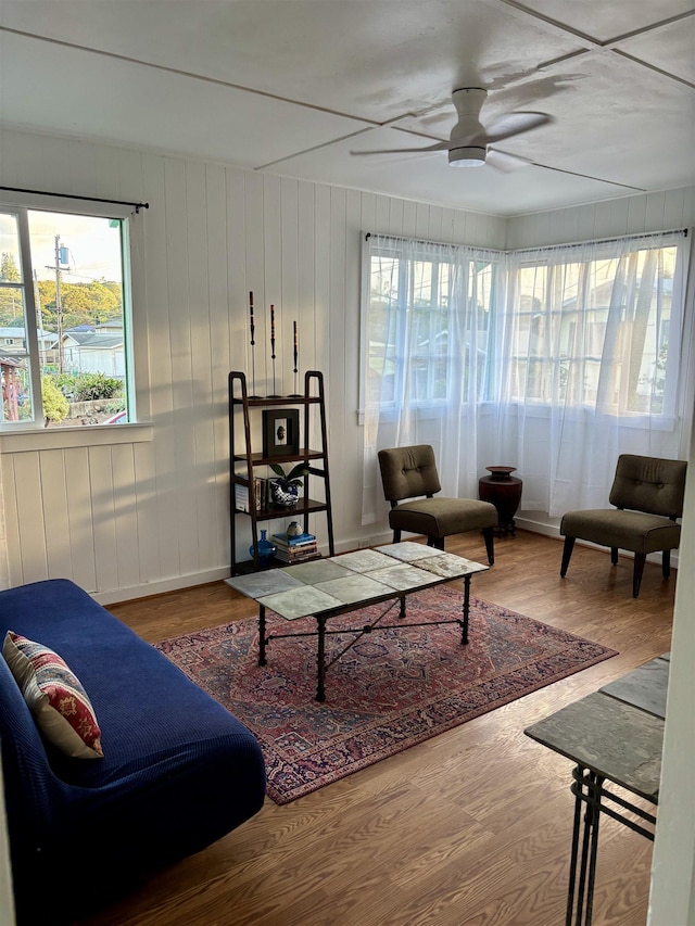 living area with a wealth of natural light, ceiling fan, and wood finished floors