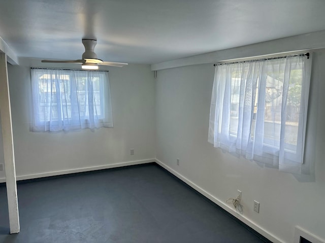 empty room with baseboards, concrete flooring, a wealth of natural light, and ceiling fan