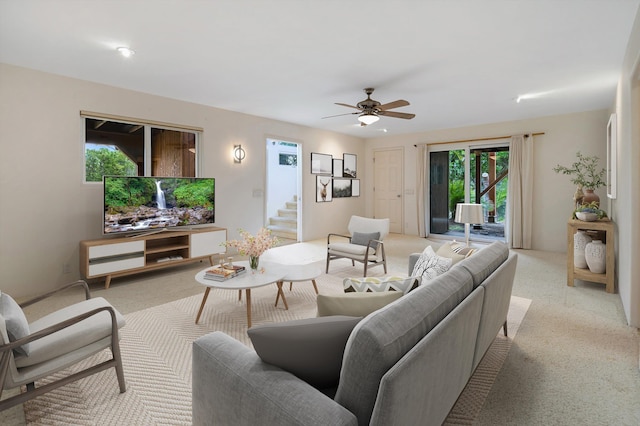 living area featuring stairway, ceiling fan, and carpet flooring