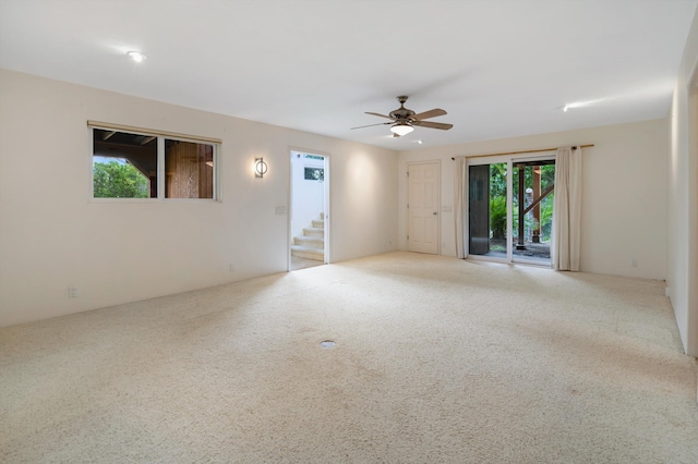 unfurnished room featuring stairs, carpet flooring, and a ceiling fan