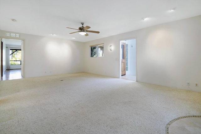 carpeted spare room featuring visible vents and ceiling fan