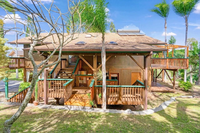 rear view of property with a deck, stairs, and a shingled roof