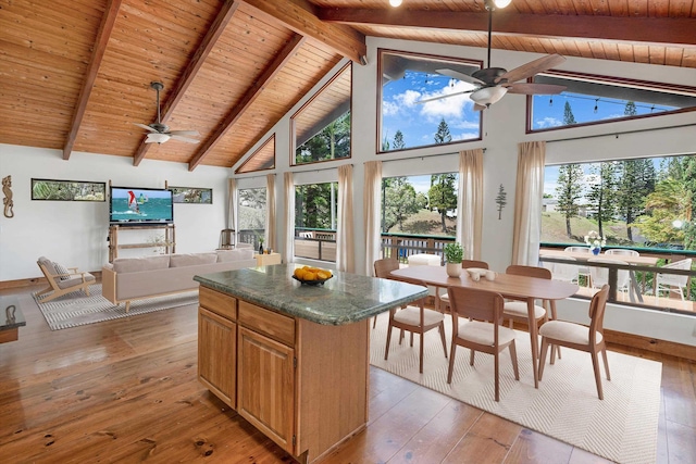 kitchen with light wood finished floors, ceiling fan, dark countertops, open floor plan, and a center island