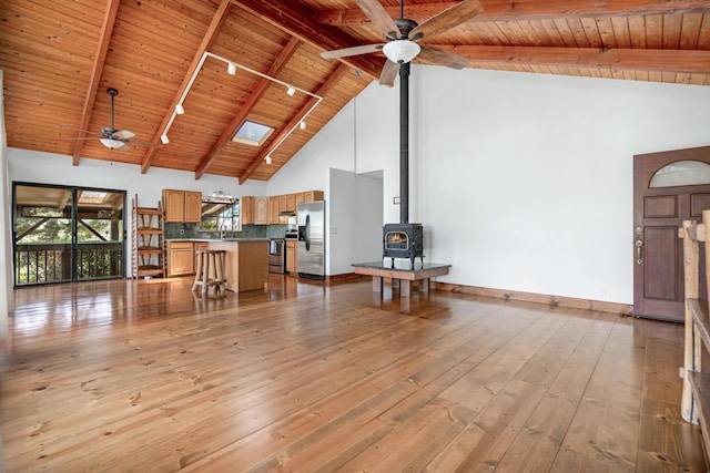 living room with baseboards, a wood stove, ceiling fan, wooden ceiling, and light wood-type flooring