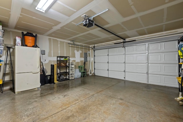 garage featuring electric panel, a garage door opener, and white refrigerator